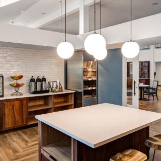 A modern kitchen with pendant lights, wood cabinetry, and an island countertop.