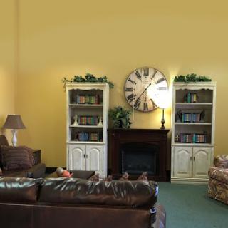 A cozy living room featuring bookshelves, a large clock, and comfortable seating.