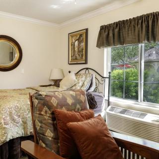 A cozy bedroom with a bed, decorative pillows, and natural light streaming in from a window.