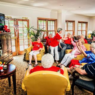 A lively group of seniors enjoying a shared moment while watching television in a cozy living room.