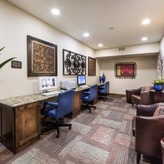A modern office space featuring desks with computers and comfortable chairs, decorated with artwork on the walls.