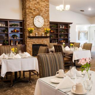 A cozy restaurant interior with neatly set dining tables and a brick fireplace.