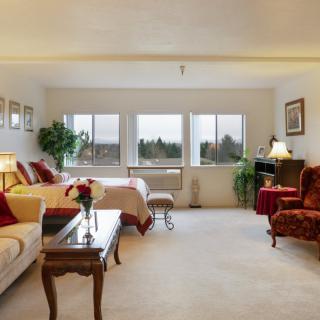 A cozy and spacious bedroom with large windows, elegant furniture, and warm decor.
