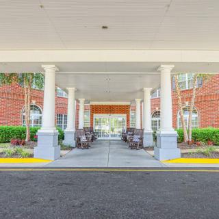 Covered entrance of a brick building with columns and landscaping.