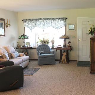 A cozy living room with a sofa, armchair, and decorative lamps by the window.