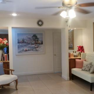 A cozy living room with a sofa, painting, and ceiling fan.