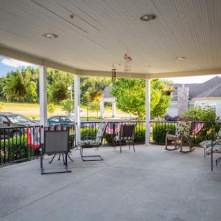 A cozy porch with seating, offering a view of the surrounding greenery.