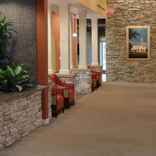 A well-decorated hallway with stone walls, red chairs, and greenery.