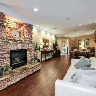 A cozy living room featuring a stone fireplace, elegant wood flooring, and modern decor elements.