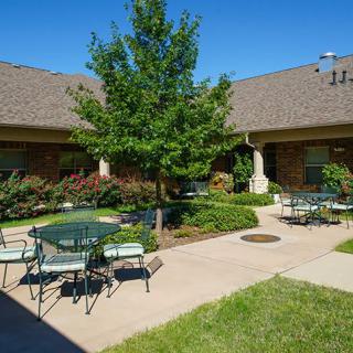 A sunny courtyard with outdoor seating and lush greenery.