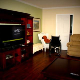 A cozy living room with a television and various seating options, including a wheelchair.