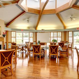 A spacious dining area with wooden furniture and large windows allowing natural light to fill the room.