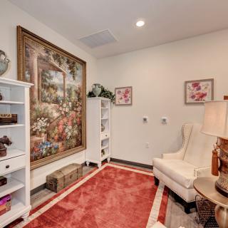A cozy living room with an armchair, bookshelves, and decorative artwork on the wall.