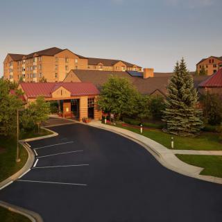 A hotel building with a driveway and surrounding greenery.