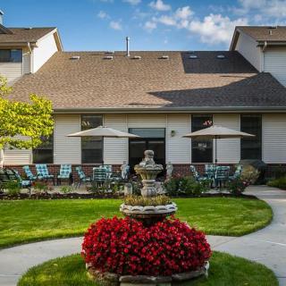 A beautiful outdoor area with a fountain surrounded by vibrant flowers and a well-maintained garden in front of a residential building.