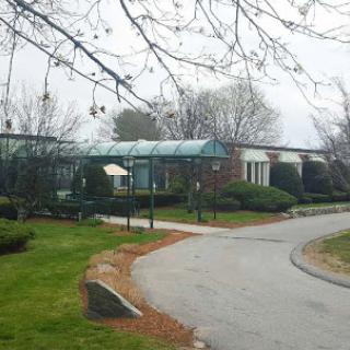 A serene pathway leading to a building surrounded by trees on a foggy day.