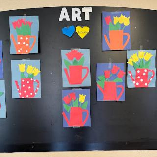 A vibrant display of children's art featuring colorful flower vases on a bulletin board.