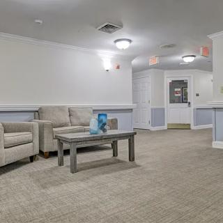 A cozy waiting area with comfortable chairs and a table, warmly lit by overhead lighting.