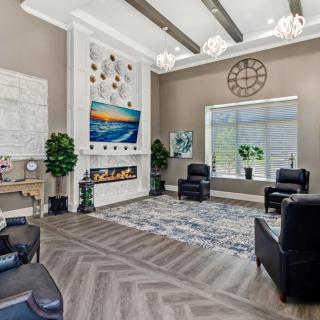 A modern living room with a fireplace, armchairs, and a large television.