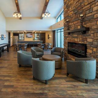 A modern lounge area with armchairs, a stone fireplace, and wooden flooring.