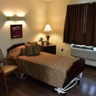A well-decorated room with a hospital bed, chair, and bedside lamp.