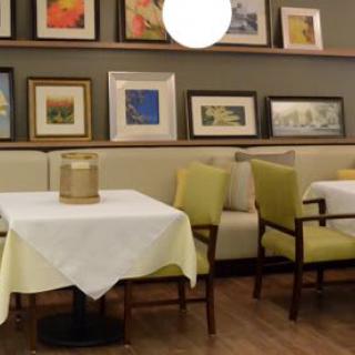 A cozy restaurant dining area with neatly arranged tables and chairs, adorned with various framed artworks on the walls.