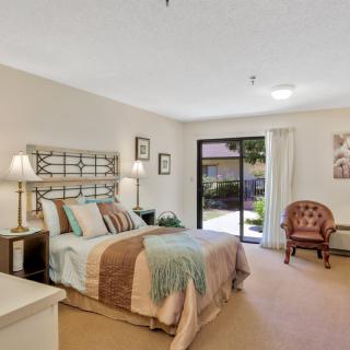A cozy bedroom with a neatly made bed, stylish lamps, and a large window providing natural light.