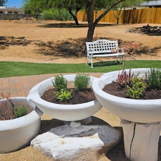 A serene outdoor space featuring decorative planters and a white bench, perfect for enjoying nature.
