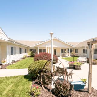 A sunny courtyard with well-maintained gardens and seating areas surrounded by a building.