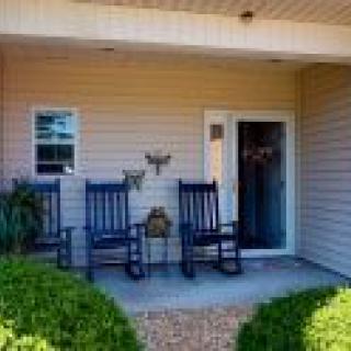 A cozy porch with two rocking chairs and potted plants beside the entrance.