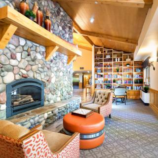A cozy lounge with a stone fireplace and comfortable seating, enhanced by a library wall.