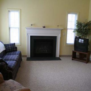 A cozy living room featuring a fireplace, sofa, and a TV in the corner.