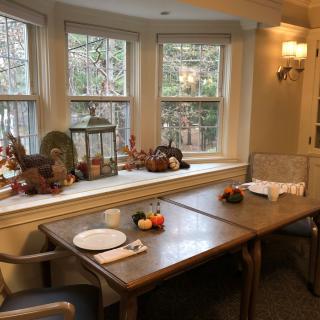 A cozy dining area with autumn-themed decorations and a view of the outdoors.