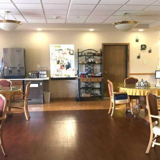 A cozy dining area featuring tables and chairs, with a beverage station against the wall.