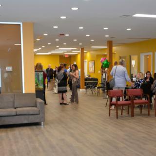A group of people socializing in a brightly lit indoor space with yellow walls and comfortable seating.