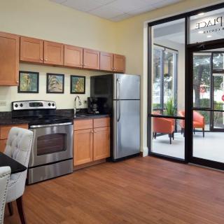 A modern kitchen with wood flooring and stainless steel appliances, featuring a large window and patio view.
