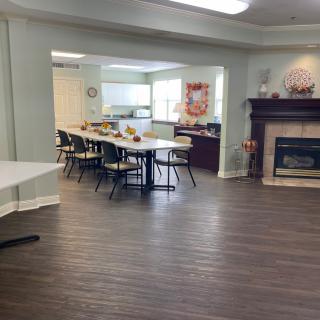 A spacious dining and meeting area with a cozy fireplace, featuring several tables and chairs arranged for a communal setting.