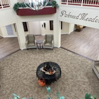 An elegant theater lobby with comfortable seating and a decorative table centerpiece under a chandelier.