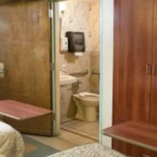 A hotel room featuring a glimpse into the bathroom, with simple furniture and decor.