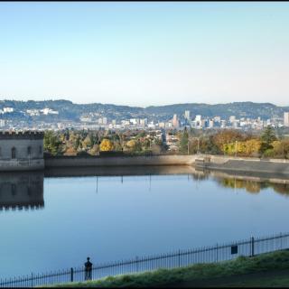 A tranquil reservoir with a city skyline in the background.