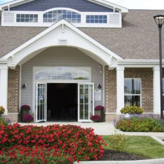A welcoming building entrance with a well-maintained garden and colorful flowers.