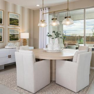 A stylish and modern dining area featuring a round table, plush white chairs, and ample natural light.