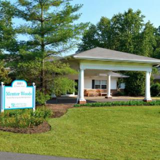 A well-maintained building entrance surrounded by greenery and a welcoming sign.