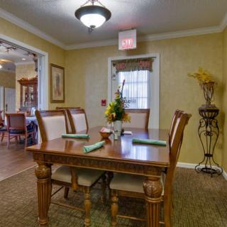 A cozy dining room with a wooden table set for four, featuring elegant decor and soft lighting.