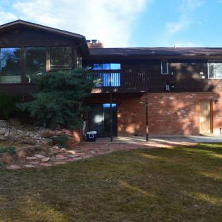 A two-story brick house with a large front lawn and clear skies.