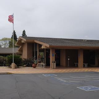 A view of a building with an American flag flying in the foreground, set against a cloudy sky.