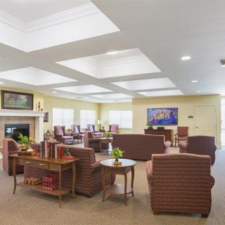 A spacious and well-lit living room with multiple seating areas, featuring sofas, tables, and a fireplace.