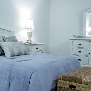 A cozy and elegantly furnished bedroom with a neatly made bed, dresser, and soft lighting.