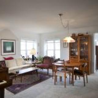 A cozy living and dining area featuring a sofa, table with chairs, a piano, and a wooden cabinet.