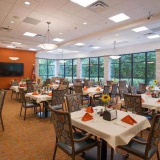 A spacious dining room with neatly set tables and large windows.